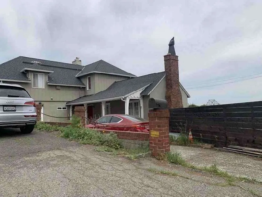 Rear elevation of 635 Longridge showing the stepped split-level roofline, brick chimney, and three stories stacked into the Oakland hillside