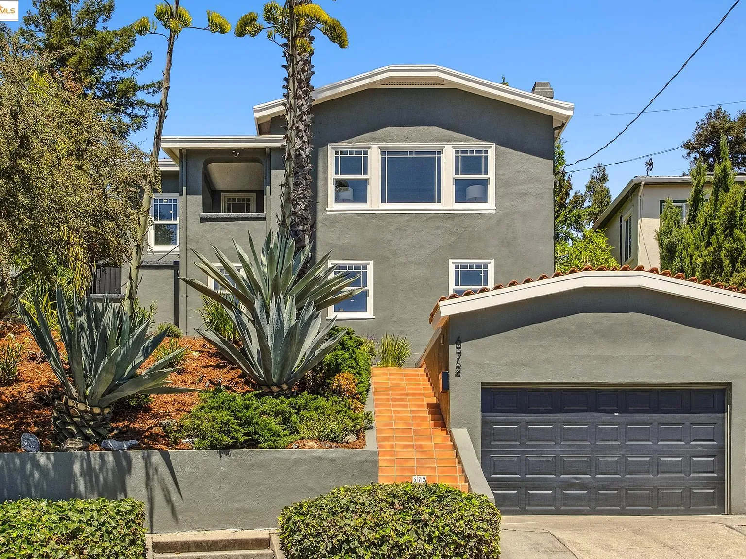 A modern stucco residence on Longridge with palm trees in the front yard and an attached single-car garage facing the street